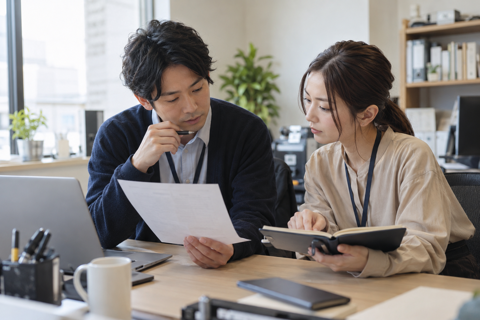 二人のPCサービス担当者が受付範囲の書類と予定表を見比べ、顧客へ伝える条件を確認する架空場面